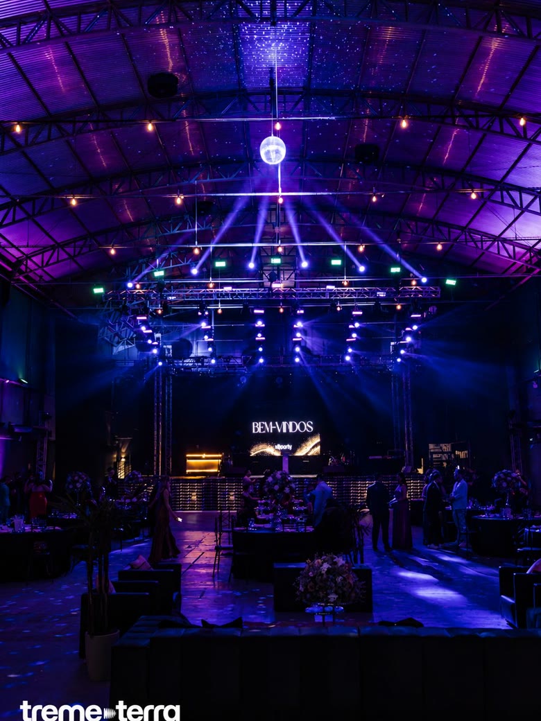 Salão de gala corporativa com bola de espelhos, feixes de luz e telão de boas-vindas