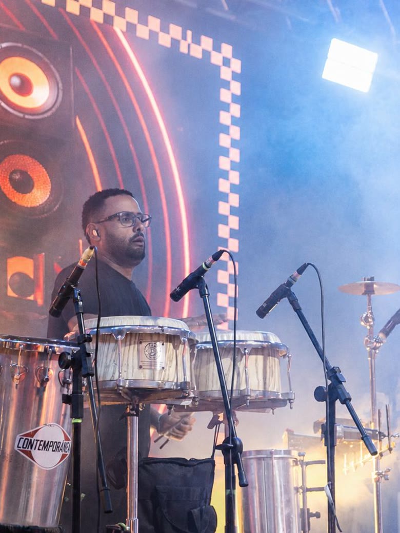 Percussionista se apresentando no Innova Show, com iluminação colorida e efeitos de fogos frios