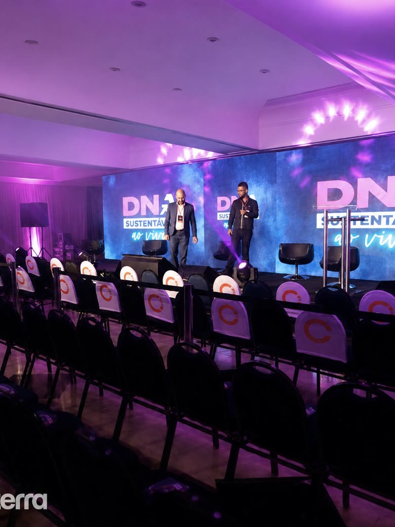 Palco montado com telão de LED para evento corporativo, plateia com cadeiras personalizadas