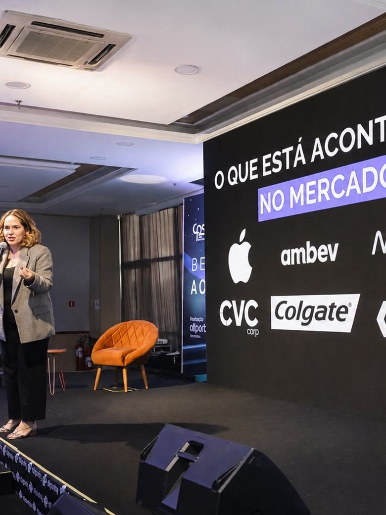 Palestrante apresentando painel de mercado em evento corporativo com telão de LED