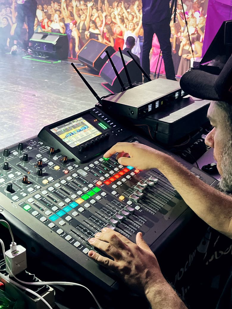 Técnico de áudio ajustando os faders da mesa de som durante o evento